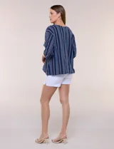 Blusa Erika de algodón con estampado de rayas en tonos azules, rosados y amarillos. Presenta cuello redondo con escote en V y botones frontales, mangas cortas decoradas con una fila de botones en los laterales y dobladillo asimétrico.