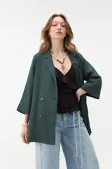 Blazer negro de corte recto y holgado, con doble botonadura frontal, solapas clásicas y mangas tres cuartos con costuras pespunteadas en contraste.