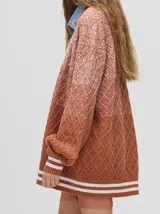 Cardigan de punto con diseño degradé en tonos tierra, patrón de rombos en relieve, cuello en V con cartera de botones y puños con rayas blancas y marrones.