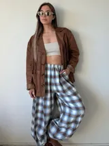 Pantalón de corte amplio y holgado, confeccionado en franela con estampado de tartán escocés en tonos azul, negro y beige. Presenta cintura elástica para un ajuste cómodo.