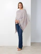 Poncho tejido en hilo soft, con efecto jaspeado multicolor (predominantemente tonos oscuros como azul marino, negro, y toques de violeta y dorado/lurex). Presenta un diseño asimétrico y flecos largos en los bordes.