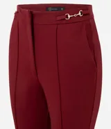 Pantalón flare de tiro alto confeccionado en tejido punto roma, con recortes frontales verticales que estilizan la silueta y detalle de hebilla metálica en la cintura.