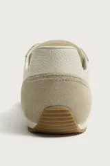 Zapatilla deportiva estilo barefoot, color marrón, con diseño de paneles en combinación de materiales y detalles en serraje. Cuenta con puntera redondeada y ancha, cordones en color crema y suela fina de goma flexible en contraste.
