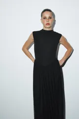 Vestido largo sin mangas con cuello subido, confeccionado con una parte superior lisa y falda de tul con caída fluida. Cuenta con cierre de cremallera oculta en la espalda.