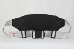 Riñonera negra de nylon con doble compartimento con cierre, correa regulable en color gris claro y parche frontal con el logo de los Dallas Mavericks.