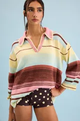 Buzo de algodón tejido, de calce relajado y silueta amplia con diseño de rayas horizontales en tonos pastel de amarillo, celeste, rosa y marrón. Tiene cuello tipo polo con terminación artesanal en crochet y mangas amplias.
