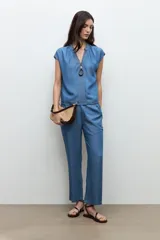 Blusa de lyocell en tono azul medio, con mangas cortas, escote en V y detalles de pespuntes decorativos en la parte frontal.