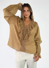 Blusa de algodón blanca con escote en V, mangas largas amplias y detalles de volados con encaje bordado en el frente.