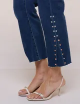 Jean crop de tiro alto, color azul, de pierna recta con terminación bootcut y detalles de tachas en los laterales.
