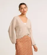 Cardigan corto de punto color beige claro, con escote en V, manga larga abullonada y cierre frontal de botones. Posee bolsillos delanteros tipo parche.