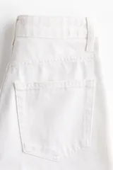 Pantalón jean de tiro alto en denim de algodón blanco, con diseño curvo de piernas con volumen y cinco bolsillos clásicos.