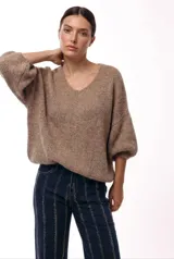 Sweater de punto color tostado con escote en V, hombros caídos y mangas 3/4 con volumen. Presenta una silueta amplia y relajada.