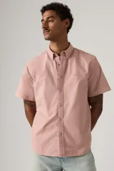 Camisa de manga corta color rosado, con cuello abotonado y cierre frontal con botones. Cuenta con sutil bordado del logo en el pecho.