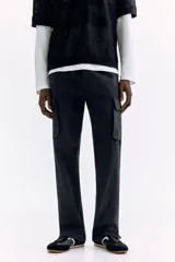 Pantalón cargo negro de nylon, de corte regular con cintura elástica ajustable con cordón. Cuenta con bolsillos laterales con cierre, bolsillos cargo con solapa en las piernas, bolsillos traseros con cierre y tensores en los tobillos.