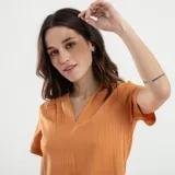 Blusa verde de manga corta con escote en V profundo y textura acanalada o plisada verticalmente. Corte holgado.