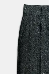 Pantalón de corte recto confeccionado en tejido con mezcla de lana. Presenta tiro medio, cintura con trabillas, bolsillos laterales y traseros, y detalle de nervio frontal. Cierre mediante cremallera, botón y ganchos metálicos.
