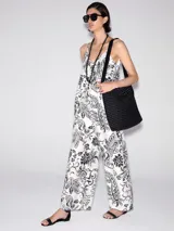 Mono largo de viscosa color blanco con estampado de flores y hojas en negro. Tiene breteles finos, corte amplio y bolsillos laterales.