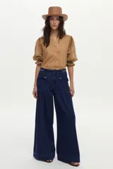 Blusa color tostado confeccionada en lino, con mangas abullonadas de ramie y detalles de bordado en punto smock en los puños.