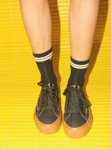 Championes de lona negra con plataforma y puntera de goma marrón, cordones negros y costuras en contraste.