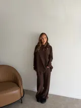 Conjunto de dos piezas compuesto por una remera de manga larga y un pantalón de corte recto, ambos confeccionados en tejido de punto texturizado color marrón.