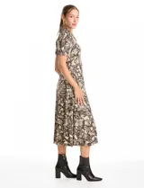 Vestido midi de seda fría con estampado animal print. Presenta cuello con solapa, escote en V con cierre frontal de botones, mangas cortas con terminación fruncida y lazo de ajuste en la cintura.