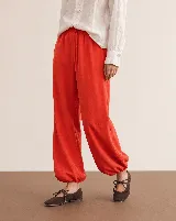 Pantalón rojo de corte holgado, estilo bombacho, con puños fruncidos en los tobillos.