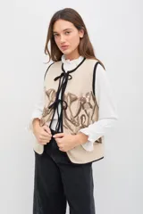 Remera de manga larga color blanco, confeccionada en tejido liviano con caída fluida. Presenta cuello alto con volados, abotonadura frontal decorativa y detalles de volados a lo largo de la abertura, además de terminaciones con volados en los puños.