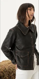 Chaqueta de cuero vacuno con acabado envejecido, diseño de cuello camisero, cierre frontal con botones metálicos y bolsillos frontales con solapa.