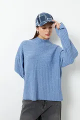 Polera gris de tejido tramado, cuello alto y mangas holgadas.