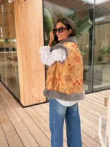 Chaleco de piel sintética en color gris, con diseño reversible. El interior presenta un forro de tela color mostaza con estampado floral bordado. Posee un corte holgado y sin mangas.