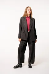 Blazer negro de tela sastrera con doble botón y dos bolsillos frontales.