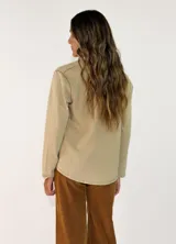 Remera de manga larga con cuello polo y cierre frontal de dos botones. Presenta un diseño de corte recto y acabado desgastado en las costuras.