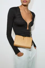 Bolso tipo clutch de formato caja rígida con cuerpo metalizado y diseño trenzado estilo cannage, con cierre de botón metálico y asa de cadena extraíble.