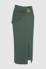 Falda midi tejida color verde oscuro, de silueta ajustada con tajo frontal en el dobladillo. Presenta un diseño drapeado en la cintura con una aplicación de pedrería decorativa y cierre posterior oculto.