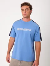 Remera de manga corta color celeste, corte holgado, con cuello redondo y diseño de bandas oscuras en los hombros con ribete blanco. Cuenta con estampado tipográfico de la marca en el pecho.