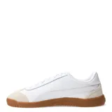 Championes Puma modelo Club 5V5 Lux, de diseño urbano con parte superior de cuero sintético blanco y detalles en gamuza beige en la puntera y el talón. Cuenta con suela de goma color caramelo y logo de la marca en dorado.