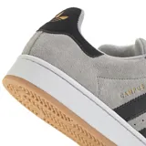 Championes Adidas modelo Campus 00s, confeccionados en gamuza gris con las icónicas tres tiras laterales en negro. Presentan un diseño de inspiración retro con suela de goma blanca y base color caramelo, cordones gruesos y detalle de marca en el talón y lateral.