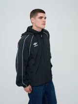 Campera rompevientos Umbro modelo Venti, de color negro con líneas blancas en las mangas y hombros, capucha con cordón de ajuste y cierre frontal completo. Cuenta con el logo de la marca bordado en el pecho.