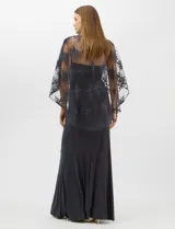 Vestido largo de corte sirena en color azul marino, confeccionado en tejido de punto con caída fluida. Presenta una capa integrada de tul fino sobre los hombros y espalda, decorada con bordados florales a tono y lentejuelas brillantes. Posee escote redondo y cierre invisible en la espalda.