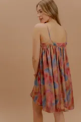 Vestido corto de silueta amplia y diseño fluido, con breteles finos y escote recto. Presenta un estampado abstracto en tonos cálidos y profundos con efecto acuarelado.