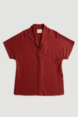 Sobrecamisa roja de lino de manga corta, con cuello solapa, costuras decorativas en contraste y cierre frontal con presillas y botones alargados.