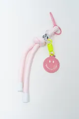 Llavero de cordón rosa con nudo, herrajes plásticos, gancho mosquetón y dije circular con cara feliz.