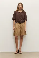 Short de lyocell color beige, de tiro alto y corte amplio, con pinzas delanteras y presillas para cinturón. Incluye un cinturón trenzado marrón oscuro con hebilla redonda forrada.