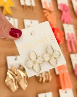 Aros colgantes con forma de flor de cuatro pétalos color blanco con borde dorado.