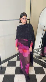 Ruana tejida de color negro con sutiles destellos plateados, diseño de líneas verticales y terminación con flecos largos en los extremos.