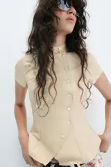 Camisa de manga corta color beige, con cuello alto mao y cierre frontal cruzado con botones.