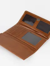 Billetera combinada de cuero en tonos marrón y camel, con solapa frontal de pelo vacuno estampado y detalle de placa con el logo de la marca.