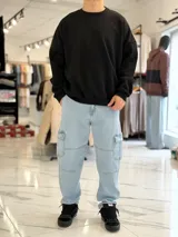 Pantalón cargo de jean azul con múltiples bolsillos en los laterales y diseño holgado.