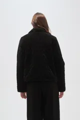 Chaqueta de poliéster con diseño capitoneado, cuello tipo camisa, cierre frontal con botones y bolsillos delanteros.