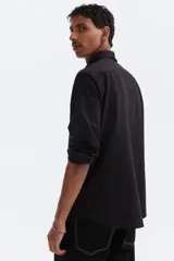 Camisa de corte ajustado en tejido de punto elástico de mezcla de algodón. Presenta cuello italiano, cierre frontal con botones, canesú en la espalda y mangas largas con puños ajustables.